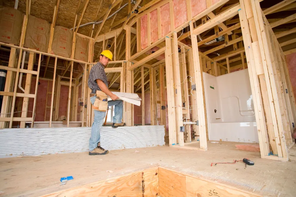 Carpenter working inside a framed-out interior with new wall and ceiling framing