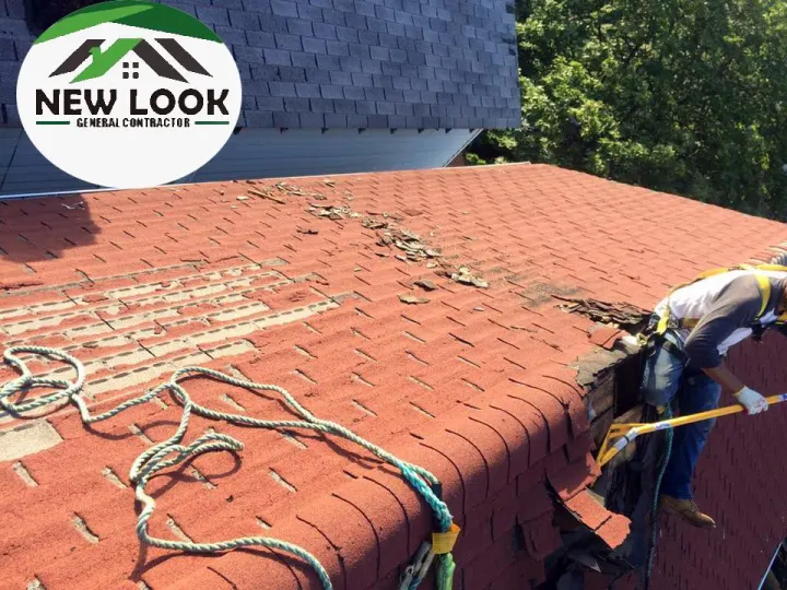 Red tile-style roof being repaired by a roofer on a rope